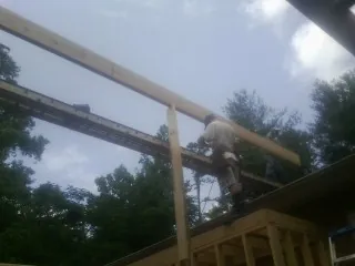 Carpenter setting a ridge beam over a new addition frame — Ice Dam Removal by Roofing Brothers in New Boston