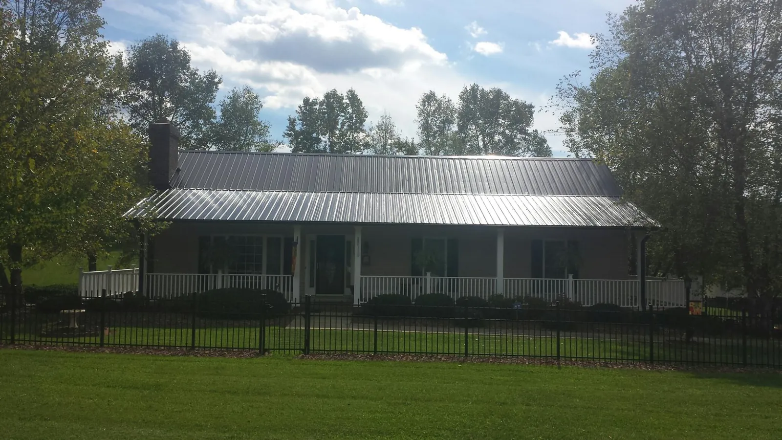 Gray metal roof on a brick ranch with a full width front porch — Gutter Guard Installation work by our crew in New Boston